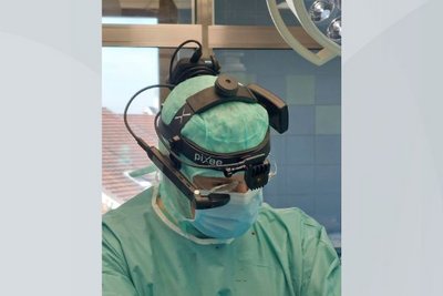 Chirurg in Schutzkleidung mit Kamera am Kopf